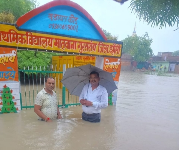 स्कूल के बाहर छाते में कमर तक पानी देख अचंभित शिक्षक