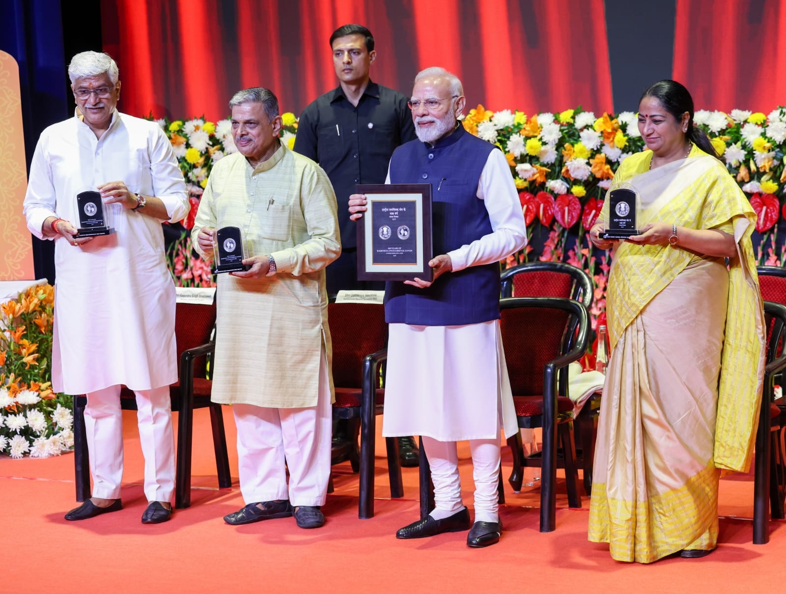 कार्यक्रम के दौरान स्मारक सिक्का जारी करते प्रधानमंत्री मोदी, सरकार्यवाह दत्तात्रेय होसबाले, मुख्यमंत्री रेखा गुप्ता एवं केन्द्रीय संस्कृति मंत्री गजेन्द्र सिंह शेखावत