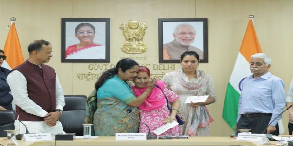 दिल्ली सचिवालय में कोविड में ड्यूटी पर जान गंवाने वाले सरकारी कर्मियों के परिजनों एक करोड़ रुपये का चेक देते मुख्यमंत्री रेखा गुप्ता