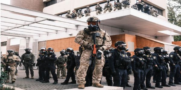 ओरेगन के पोर्टलैंड में पिछले माह विरोध प्रदर्शनों के दौरान संघीय आव्रजन केंद्र की सुरक्षा  में तैनात नेशनल गार्ड। साभार फोटो - द न्यूयॉर्क टाइम्स