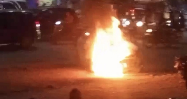 सील किशन होंडा के सामने खड़ी कार में अचानक आग लगने के बाद दमकल कर्मी आग बुझाते हुए, सड़क पर अफरा-तफरी का मंजर।