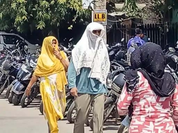 फरीदाबाद में तेज धूप में मुंह और चेहरे ढककर गतव्य की ओर जाते लोग।