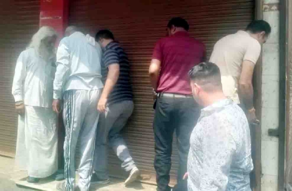 सेक्टर-23 संजय कॉलोनी में शराब के ठेके पर ताला लगाते लोग।