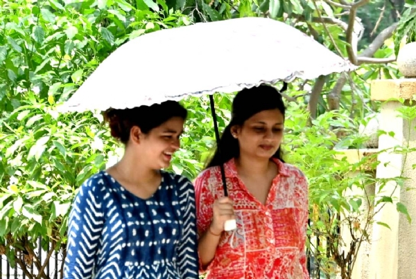 कानपुर में तेज धूप और नौतपा से बचने के लिए घर से निकली युवतियां हाथों में छाता लेकर जाती हुई का छायाचित्र