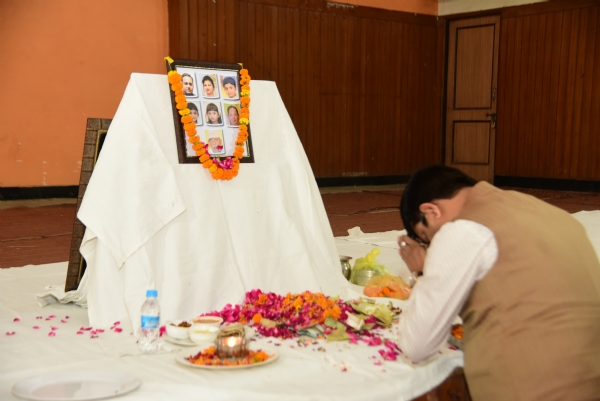 मृतकों के चित्र पर पुष्प अर्पित कर शोक व्यक्त करते मंत्री नंदी