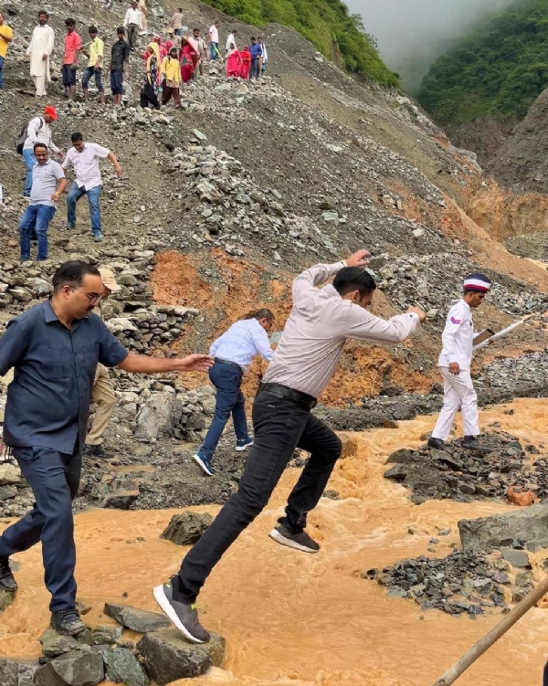 गांव पहुंचने के लिए रास्ता पार करते डीएम।