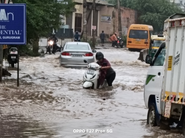 बरसात के भरे पानी में स्कूटी बंद होने से परेशान युवती।