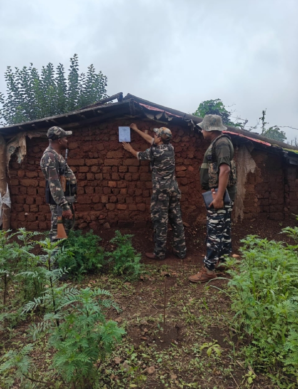 नक्सली के विरुद्ध  जारी इस्तेहार की तामिला करते पुलिस कर्मी