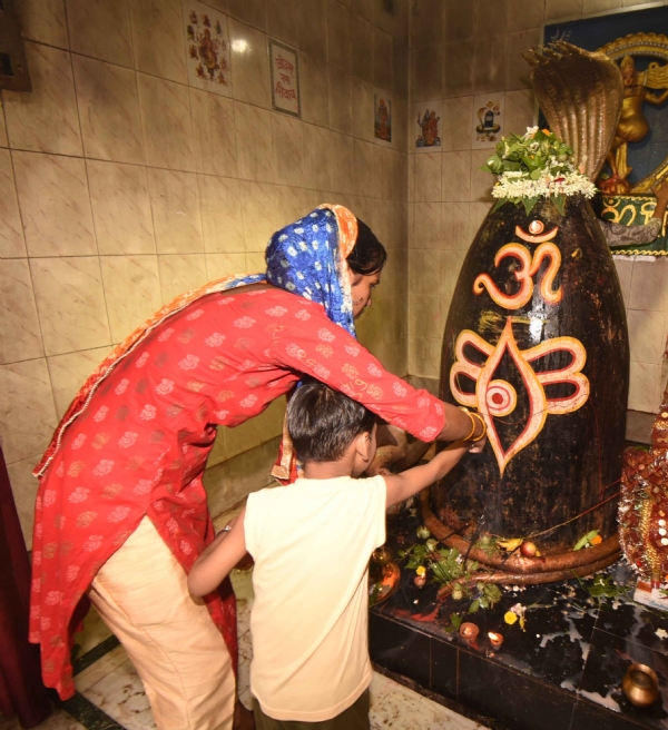 श्रावण के पहले सोमवारी को शिव मंदिर में भगवान शिव का अभिषेक करते श्रद्धालु