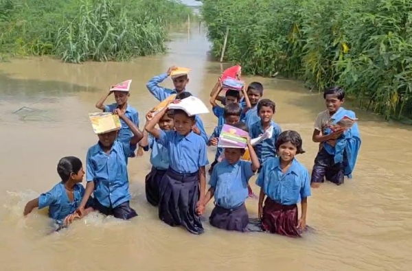 पानी के बीच स्कूल जाते बच्चे