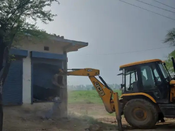 अवैध दुकान को तोड़ते हुए जेसीबी।