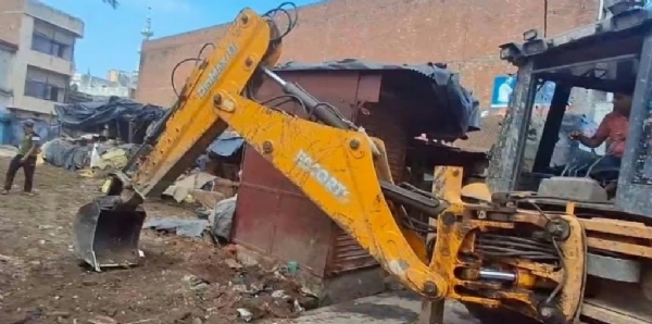 संभल की सब्जी मंडी में दुकानों को ध्वस्त करती जेसीबी।
