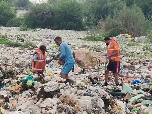 शव को दलदल में से निकालते हुए कर्मचारी।