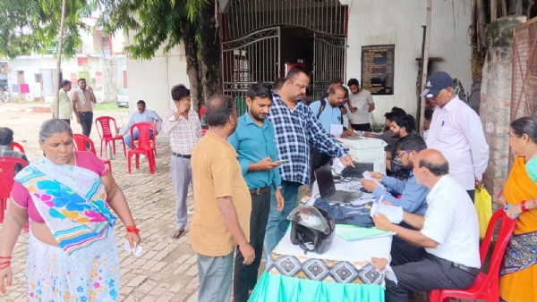 मढ़ीनाथ क्षेत्र में आयोजित संपत्ति कर समाधान शिविर में बकाया कर जमा करते भवन स्वामी और जानकारी देते नगर निगम कर्मी।