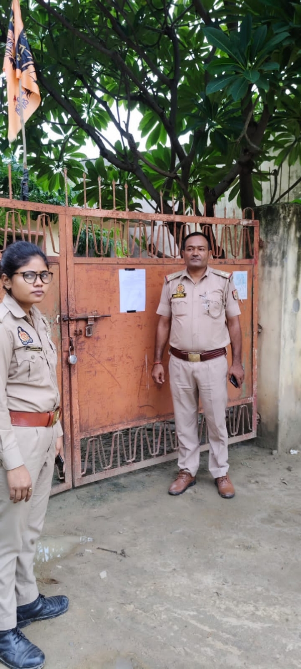 भगोड़े के घर नोटिस चस्पा करते हुए पुलिस