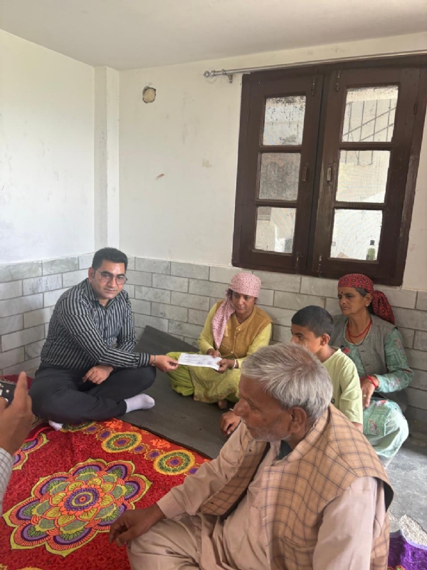 सहायता राशि का चेक भेंट करते हुए जिला विकास अधिकारी।