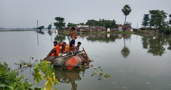 ड्रम के नाव पर पार करते लोग
