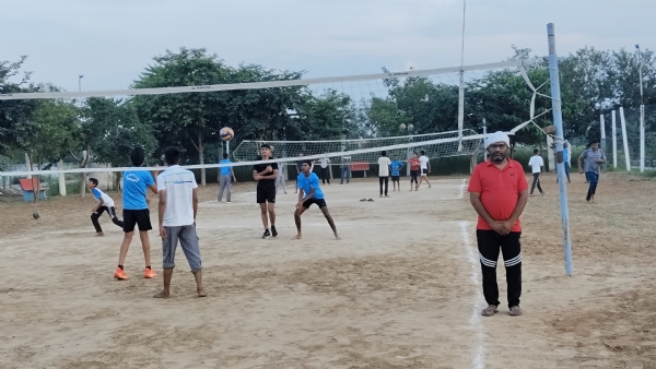 स्टेडियम में वॉलीबॉल मैच खेलते युवा।
