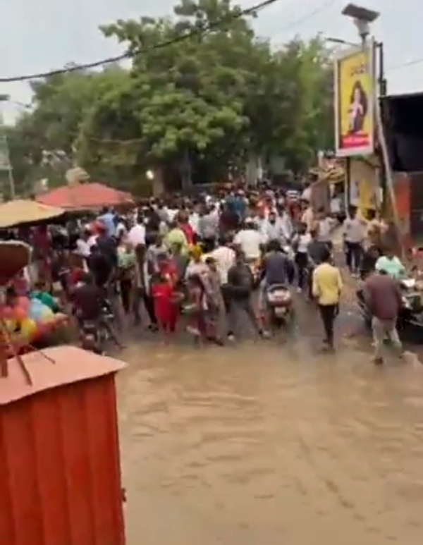 गंगा का जल सड़क तक पहुंचने पर उससे गुजरते लोग (वीडियो से ली गई फोटो)