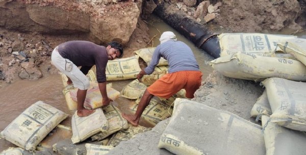 सिमेन्ट की बोरी से सड़क के गढ्ढों को भरते ग्रामीण।