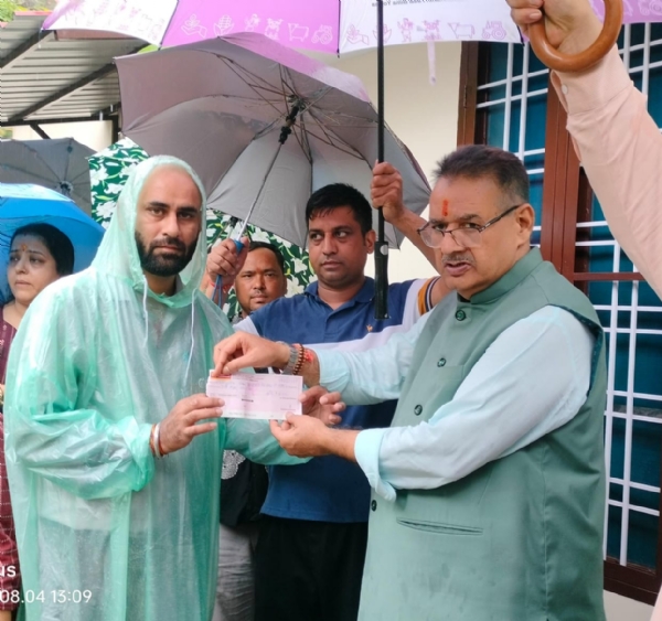 कैबिनेट मंत्री गणेश जोशी  पीड़ितों को राहत राशि के चेक वितरित करते।