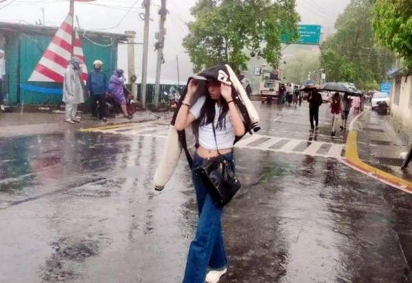 नैनीताल में बारिश के दौरान माल रोड पर गुजरती एक युवती।