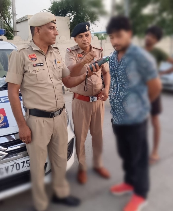 कार चालक का ब्रेथ एनालाइजर से एल्कोहल टैस्ट करते पुलिस अधिकारी।