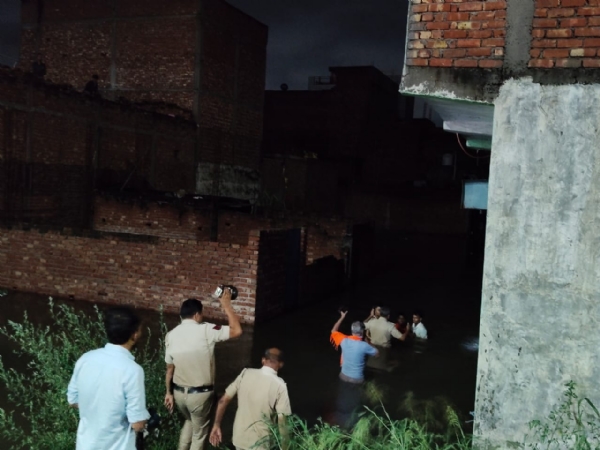 दिल्ली के बाबा हरिदास नगर थाना क्षेत्र के गीतांजलि एन्क्लेव, झाड़ोदा कलां  में मंगलवार  रात पानी भरने के बाद लोगों को सुरक्षित स्थानों  पहुंचाते पुलिसकर्मी