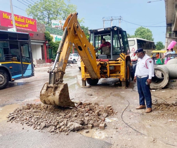 गुरुग्राम में सडक़ के गड्ढे भरवाते यातायात पुलिसकर्मी।