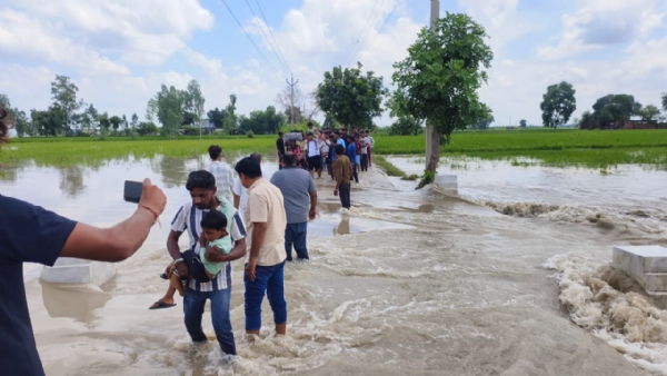 जलभराव वाले इलाकों से लोगों को सुरक्षित स्थान पर ले जाते कर्मचारी