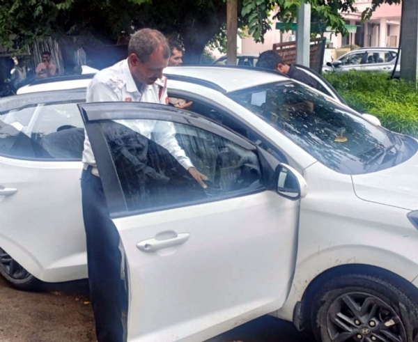 कार की खिड़की पर लगी ब्लैक फिल्म को उतारता ट्रैफिक पुलिस अधिकारी।