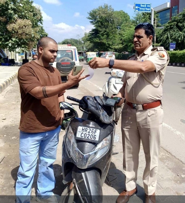 गुरुग्राम पुलिस आयुक्त कार्यालय के सामने उस स्कूटी को जब्त करते यातायात पुलिस अधिकारी, जिसके28 चालान की राशि दो लाख से अधिक बकाया है।