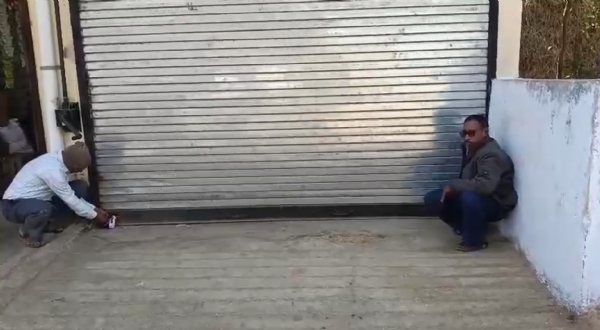 गोदाम को सील लगाते हुए कर्मचारी।