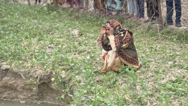 गड्ढे को देखते पीड़ित महिला किसान गड्ढे को देखते पीड़ित महिला किसान