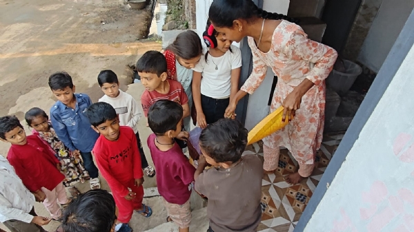 बच्चों को अनाज देती हुई महिला। बच्चों को अनाज देती हुई महिला।