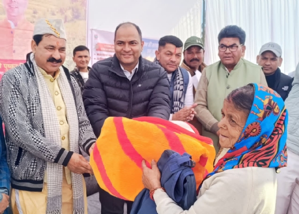 शिविर में गरीब महिला को कंबल वितरित करते जिला अधिकारी