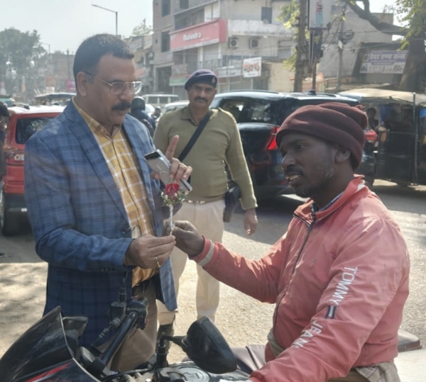 गुलाब का फूल देते अधिकारी