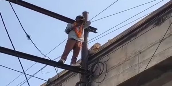 आंखों पर चश्मा, गले में माला, विद्युत पोल पर चढ़ा युवक
