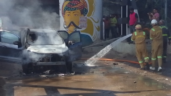 जलती कार की आग बुझाते पुलिस कर्मी