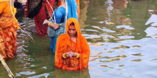 उगते सूर्य को अर्घ्य देती महिला