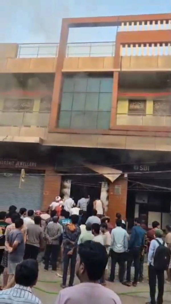 बैंक में लगी आग बुझाते हुए लोग