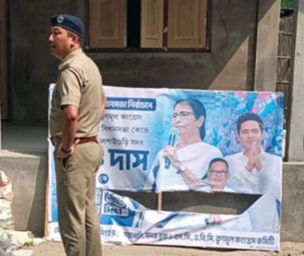 तृणमूल कांग्रेस का फटे पोस्टर को देखते पुलिस कर्मी