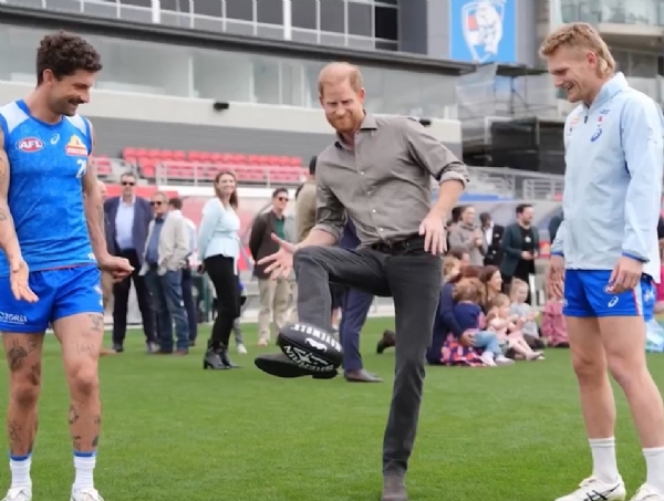 प्रिंस हैरी बुलडॉग्स के सितारों  टॉम लिबरेटर, एडम ट्रेलोअर और मैथ्यू केनेडी के साथ किकिंग (किक मारने) के कौशल का प्रदर्शन करते। फोटो - द ऑस्ट्रेलियन