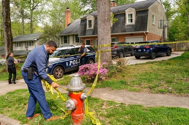 जस्टिन फेयरफैक्स का घर वर्जीनिया के एनांडेल में है। 16 अप्रैल, 2026 को उनके घर के बाहर एक हाइड्रेंट पर एक पुलिस अधिकारी कॉर्डन टेप लगाता। फोटो - इंटरनेट मीडिया