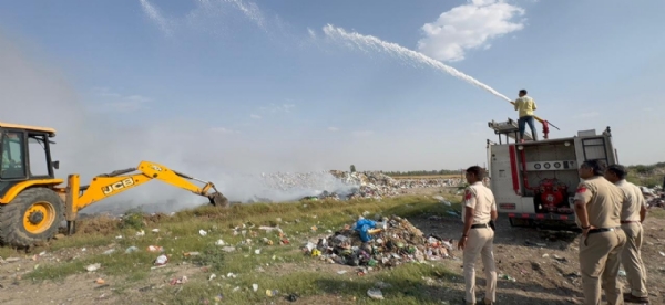 आग बुझाने का प्रयास करते दमकल कर्मी व आग को फैलने से रोकने के गड्डे खोदती जेसीबी मशीन।