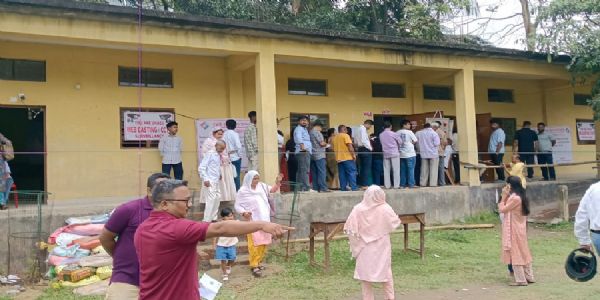 असम चुनाव 2026: गुवाहाटी के बरसोजाई हाई स्कूल मतदान केन्द्र पर गुरुवार को बरसात के बीच मतदान करने के लिए कतारबद्ध मतदाता