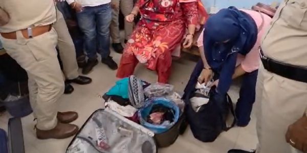 महिलाओं के सूटकेस की जांच करती पुलिस