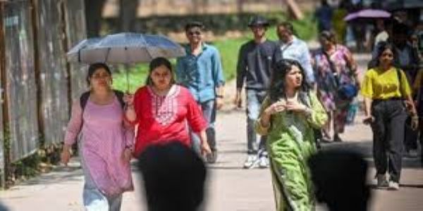 लोग भीषण गर्मी से बचाव के लिए छतरी का उपयोग करते हुए।
