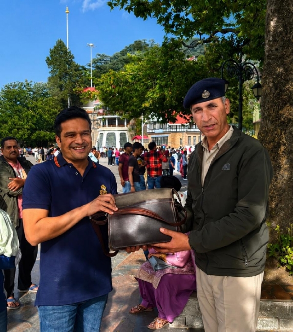 पर्यटक को बैग लौटाता पुलिस कर्मी पर्यटक को बैग लौटाता पुलिस कर्मी