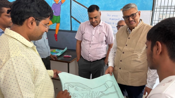 बच्चों द्वारा बनाई गई पेंटिंग देखते अधिकारी।